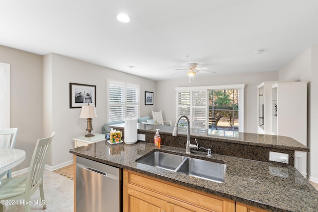 kitchen featuring stainless steel dishwasher, plenty of natural light, dark stone countertops, and sink