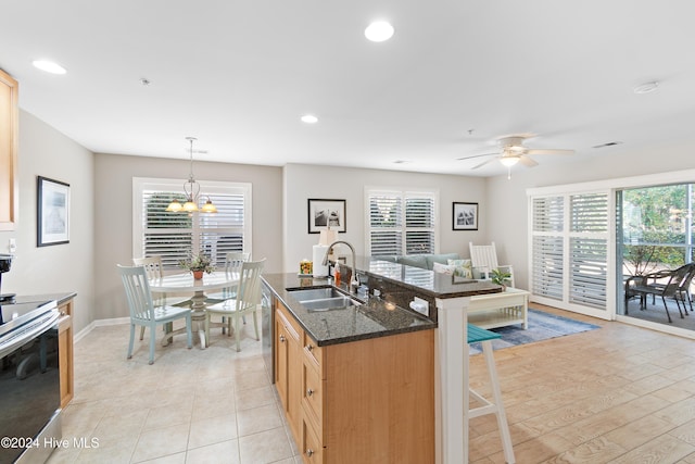 kitchen featuring a kitchen breakfast bar, stainless steel appliances, sink, pendant lighting, and dark stone countertops