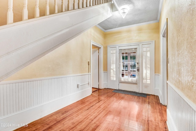 foyer featuring a textured ceiling, hardwood / wood-style flooring, and crown molding