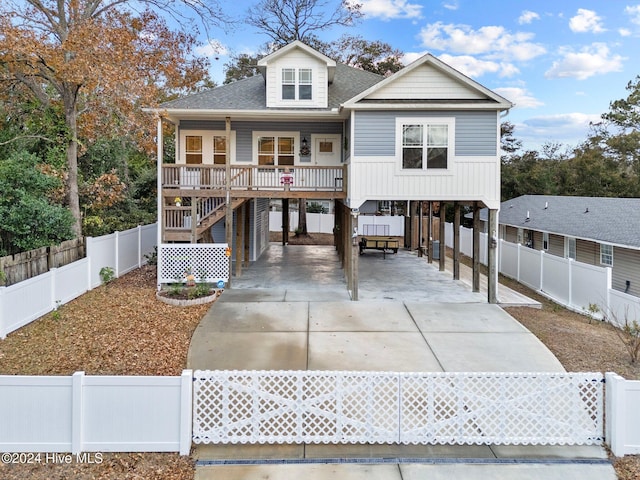 raised beach house featuring covered porch and a carport