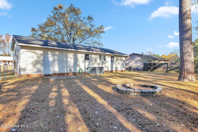 rear view of house with central AC unit and an outdoor fire pit