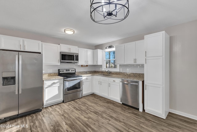 kitchen featuring an inviting chandelier, hanging light fixtures, appliances with stainless steel finishes, white cabinetry, and wood-type flooring