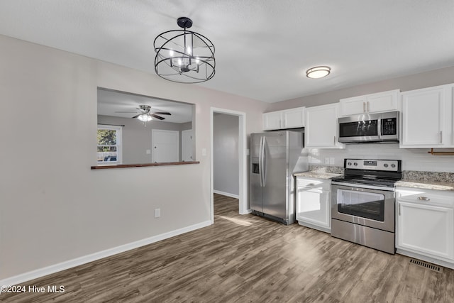 kitchen featuring ceiling fan with notable chandelier, hanging light fixtures, white cabinetry, wood-type flooring, and stainless steel appliances