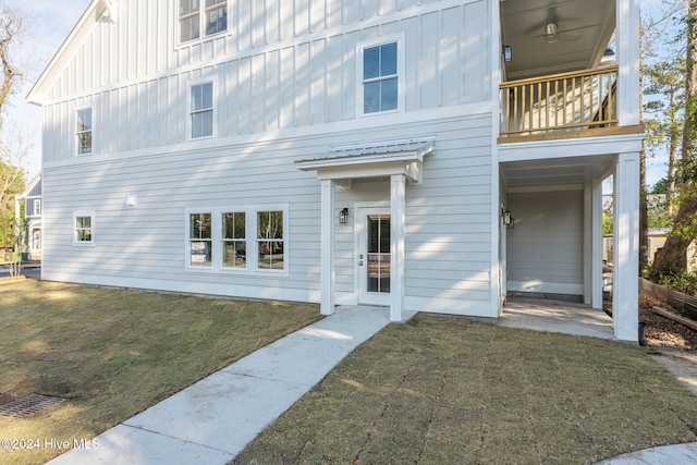 view of front of property with a front yard, a balcony, and ceiling fan