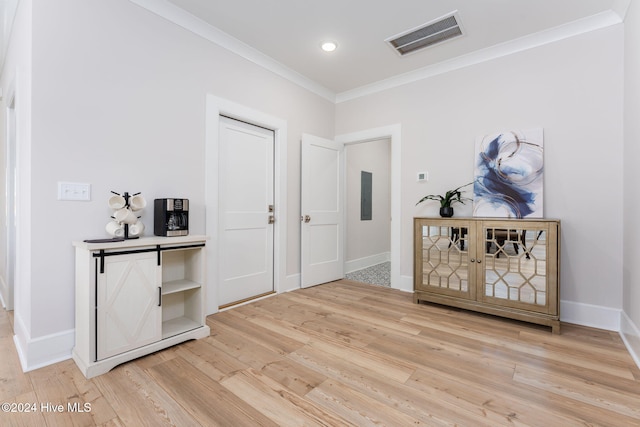 foyer entrance with wood-type flooring, electric panel, and crown molding