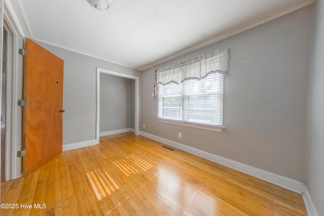 unfurnished bedroom featuring hardwood / wood-style flooring, ornamental molding, and a closet