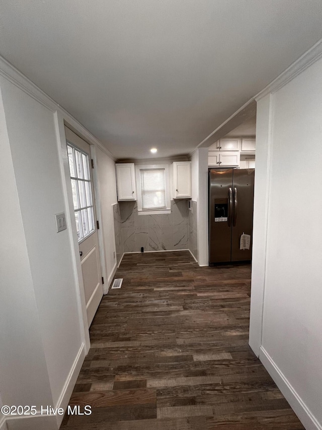 kitchen with white cabinetry, crown molding, dark wood-type flooring, and stainless steel fridge