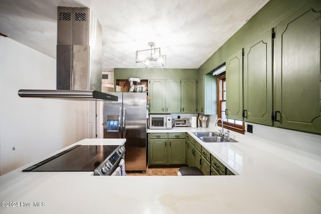 kitchen with range, sink, stainless steel fridge, island range hood, and green cabinets