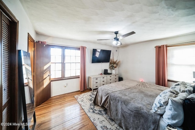 bedroom with ceiling fan, multiple windows, and light hardwood / wood-style floors