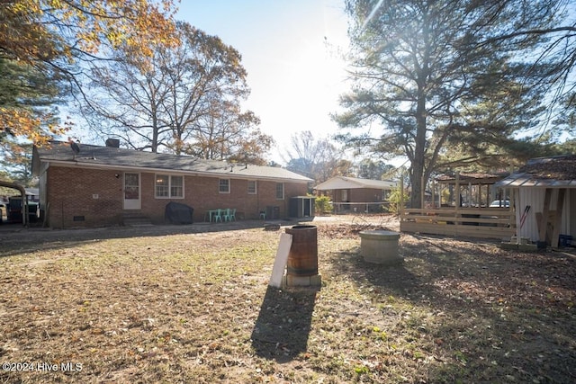 rear view of house featuring a lawn and central AC