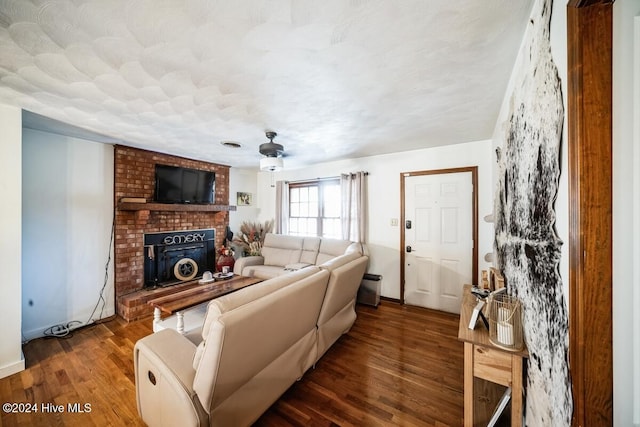 living room featuring ceiling fan, dark hardwood / wood-style flooring, and a brick fireplace