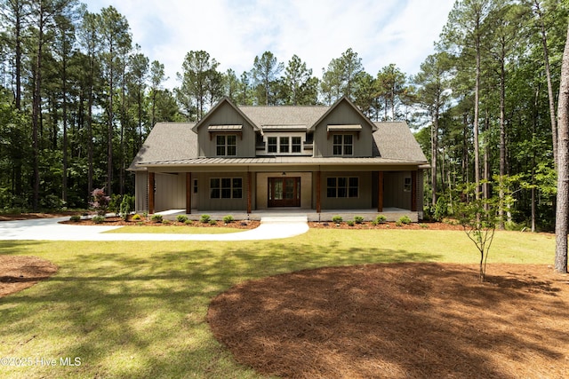 view of front facade with board and batten siding, a front lawn, covered porch, and a shingled roof