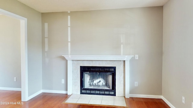 details with a tile fireplace and wood-type flooring