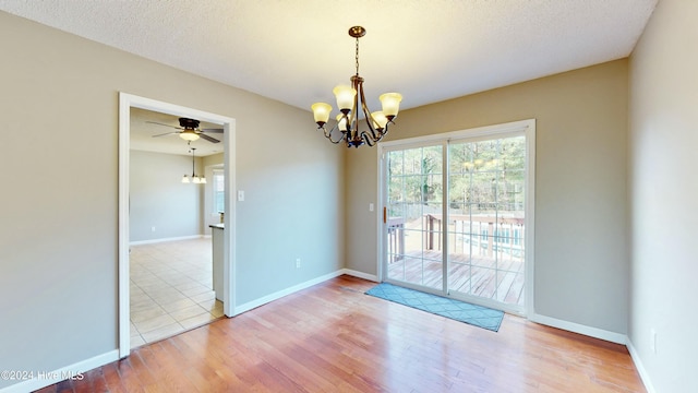 empty room featuring a textured ceiling, hardwood / wood-style floors, and ceiling fan with notable chandelier