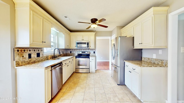 kitchen featuring appliances with stainless steel finishes, backsplash, light stone counters, and ceiling fan