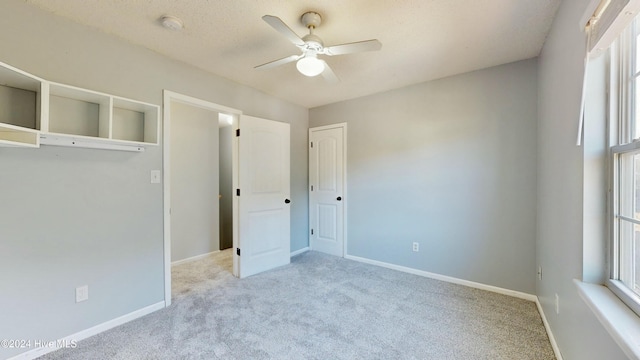 unfurnished bedroom featuring a textured ceiling, ceiling fan, light carpet, and a closet