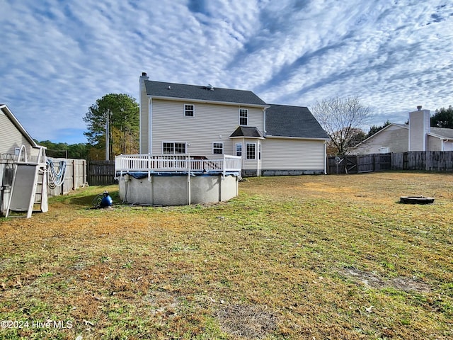 back of property with a lawn and a covered pool