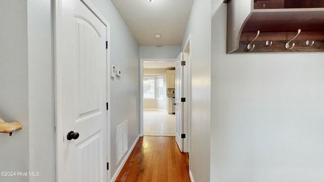 corridor featuring a textured ceiling and hardwood / wood-style flooring