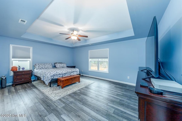 bedroom featuring hardwood / wood-style floors, a tray ceiling, and ceiling fan