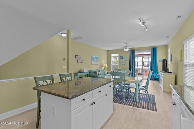 kitchen featuring white cabinetry, a breakfast bar, a kitchen island, and light wood-type flooring