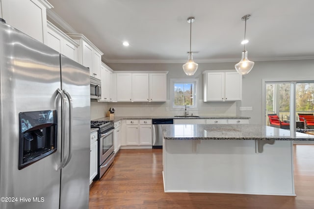 kitchen featuring stone counters, sink, white cabinets, a kitchen island, and appliances with stainless steel finishes