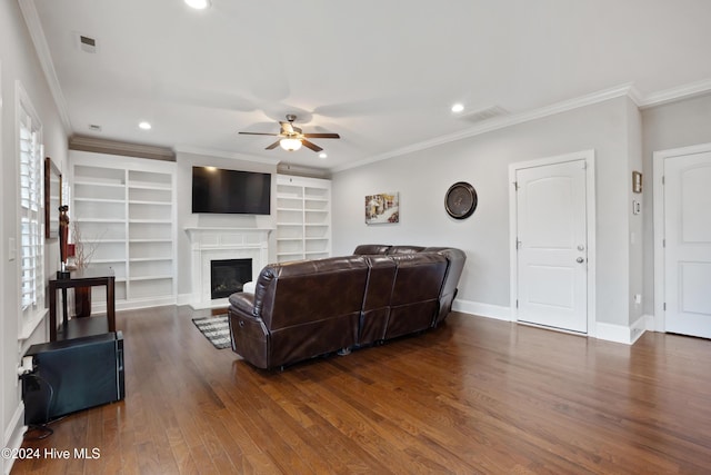 living room with built in shelves, ceiling fan, ornamental molding, and dark hardwood / wood-style floors