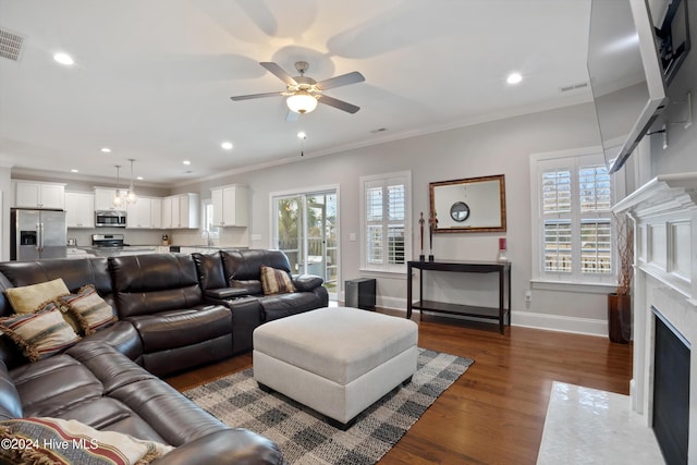 living room with ceiling fan, sink, a premium fireplace, dark hardwood / wood-style flooring, and ornamental molding