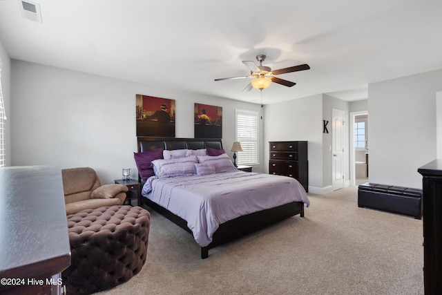 carpeted bedroom with ceiling fan, connected bathroom, and multiple windows