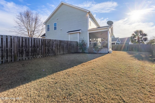 back of property featuring a lawn and a sunroom