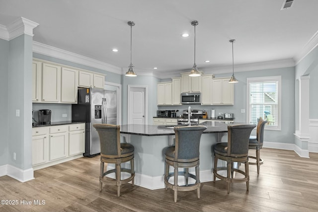 kitchen with light hardwood / wood-style flooring, pendant lighting, an island with sink, and appliances with stainless steel finishes