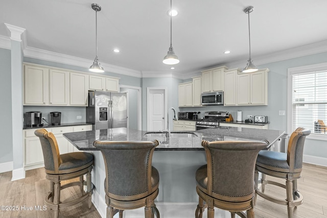 kitchen featuring sink, light hardwood / wood-style floors, hanging light fixtures, a center island with sink, and appliances with stainless steel finishes