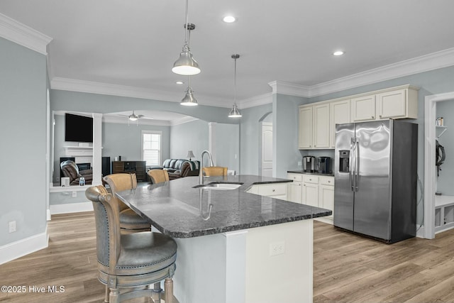 kitchen with a kitchen island with sink, stainless steel fridge with ice dispenser, hanging light fixtures, ceiling fan, and sink