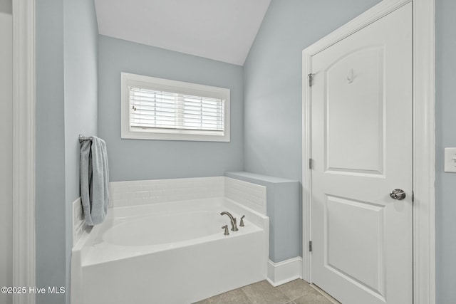 bathroom with a bath, vaulted ceiling, and tile patterned floors