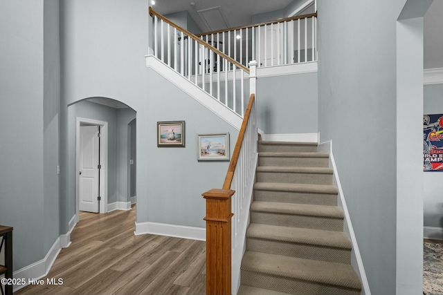 staircase with a towering ceiling and hardwood / wood-style floors