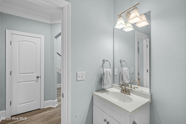 bathroom with ornamental molding, vanity, and wood-type flooring