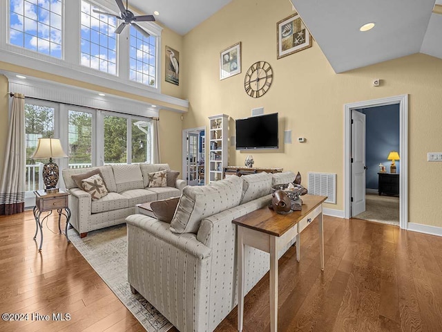 living room with ceiling fan, a high ceiling, and hardwood / wood-style flooring