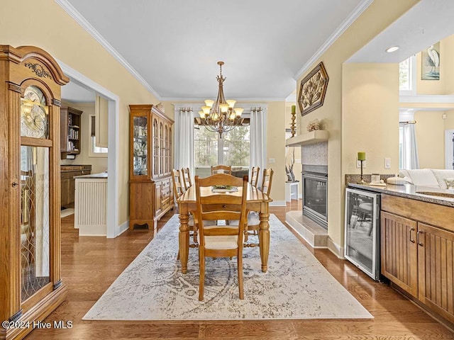 dining area with ornamental molding, a fireplace, beverage cooler, and a notable chandelier