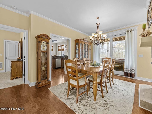 dining space with dark wood-type flooring, a chandelier, and ornamental molding