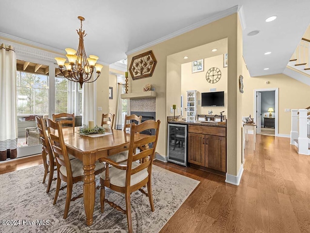 dining room featuring a notable chandelier, light wood-type flooring, ornamental molding, and beverage cooler