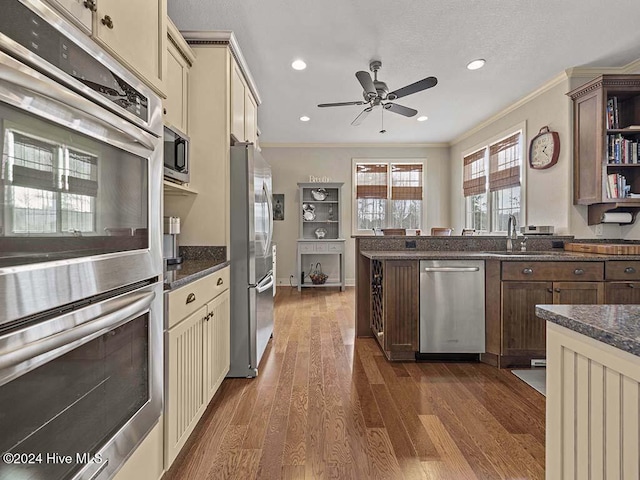 kitchen with cream cabinetry, dark hardwood / wood-style floors, crown molding, and appliances with stainless steel finishes