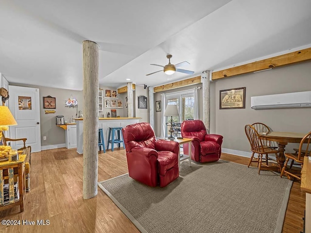 living room with an AC wall unit, ceiling fan, decorative columns, and light hardwood / wood-style floors