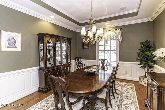 dining room with dark hardwood / wood-style floors, a tray ceiling, ornamental molding, and a notable chandelier