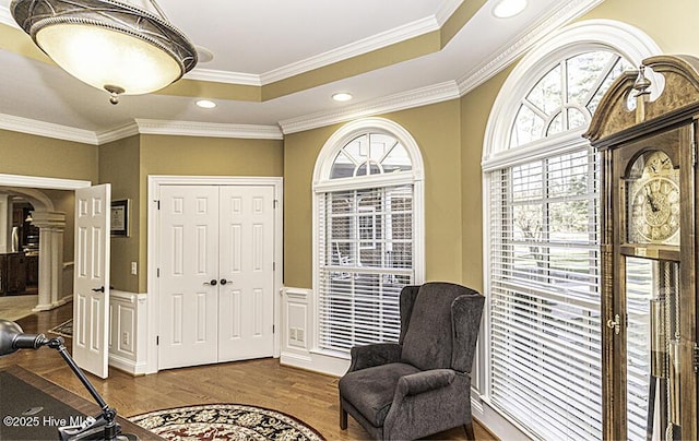 sitting room featuring wood-type flooring, a raised ceiling, and ornamental molding