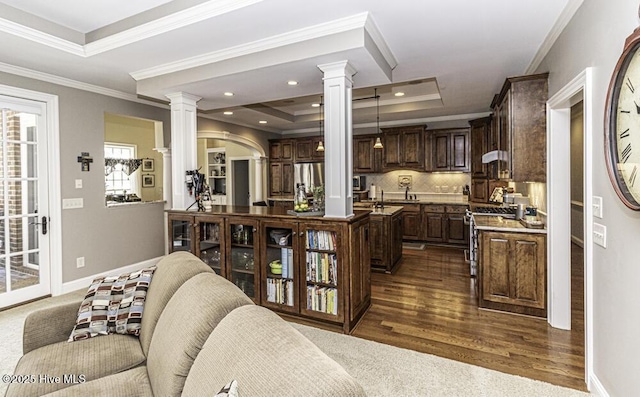 living room featuring crown molding, dark hardwood / wood-style flooring, a tray ceiling, and decorative columns