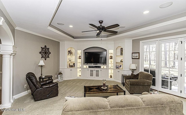 carpeted living room with ornate columns, crown molding, a tray ceiling, and ceiling fan