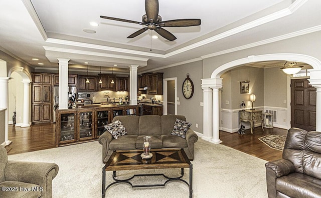 carpeted living room with ceiling fan, ornamental molding, and a raised ceiling