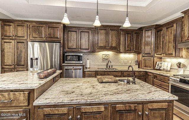 kitchen with hanging light fixtures, appliances with stainless steel finishes, sink, and a center island with sink