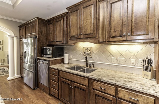 kitchen featuring sink, dark wood-type flooring, ornamental molding, stainless steel appliances, and ornate columns