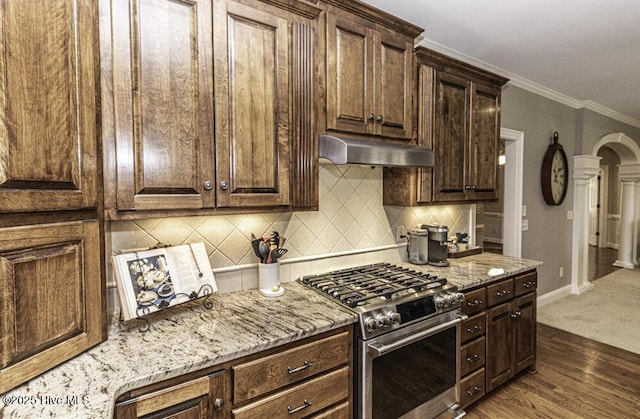 kitchen with stainless steel range with gas cooktop, dark wood-type flooring, dark brown cabinets, light stone countertops, and crown molding