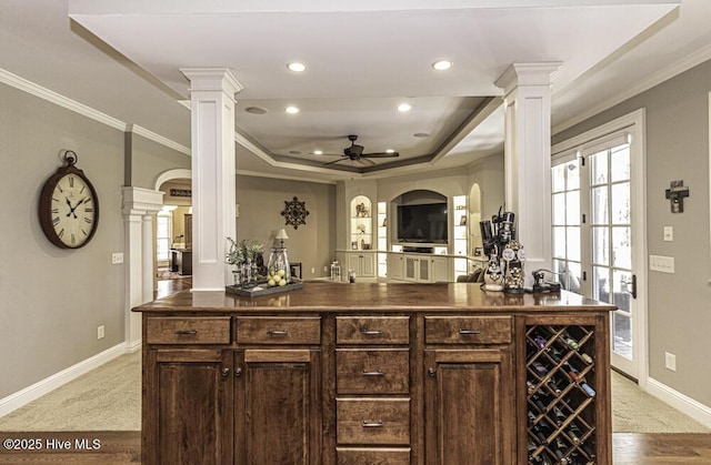 bar featuring crown molding, ceiling fan, dark brown cabinets, and a tray ceiling